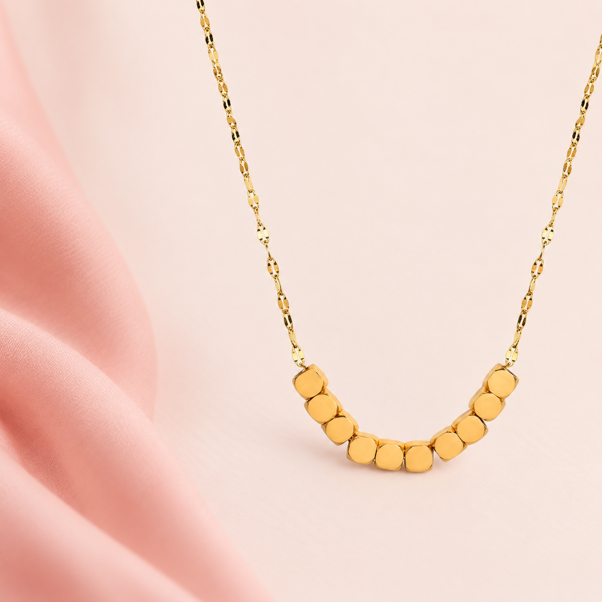 Gold-tone necklace with ten rounded-square beads at the front