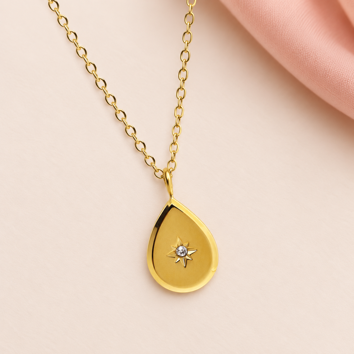 Gold-tone teardrop pendant necklace with a star-shaped central accent