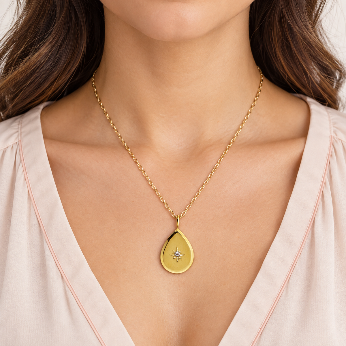 Gold-tone teardrop pendant necklace with a star-shaped central accent