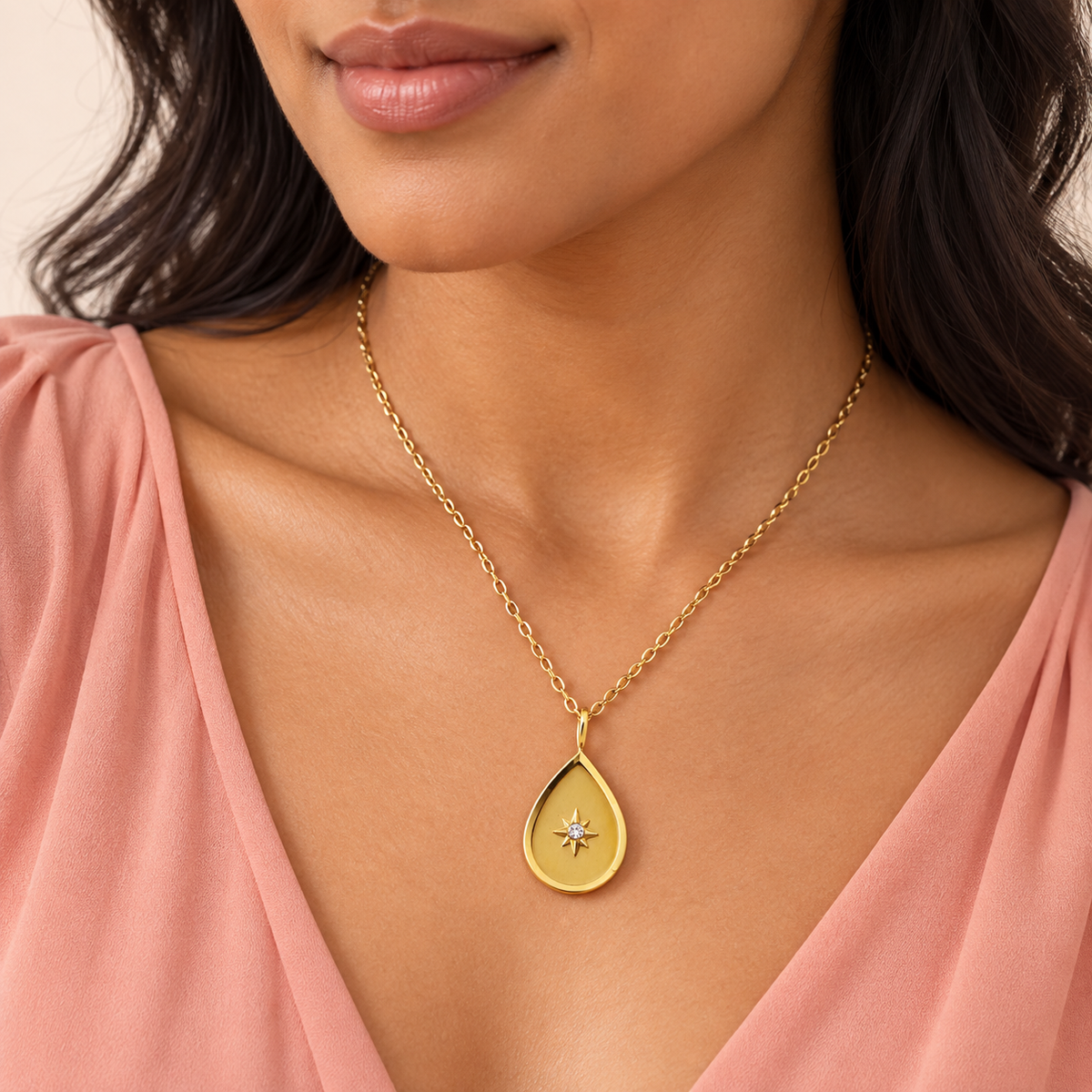 Gold-tone teardrop pendant necklace with a star-shaped central accent
