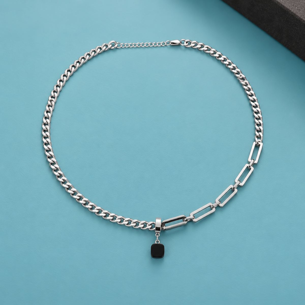Silver-tone link necklace with a black rounded-square pendant on aqua