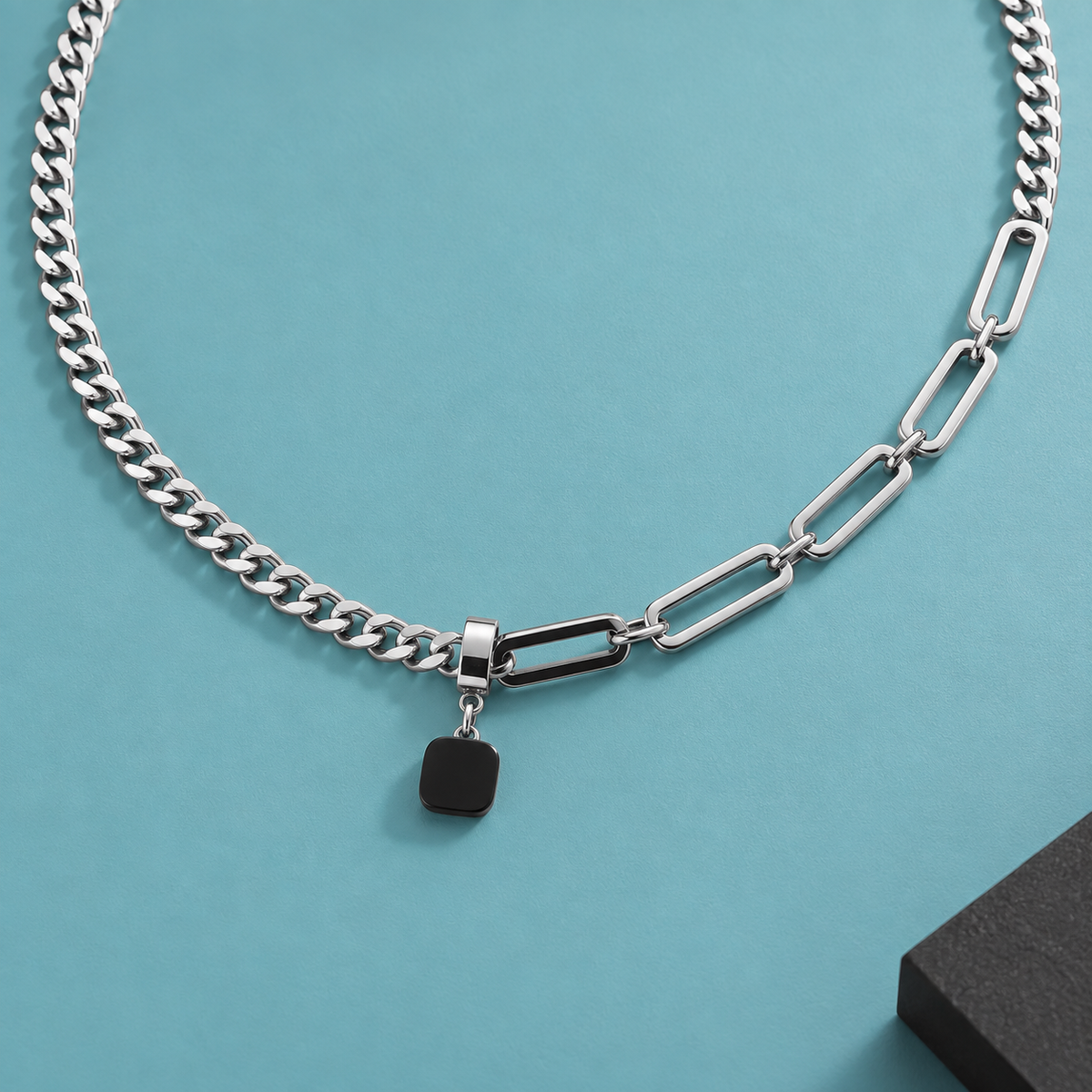 Diagonal detail of the necklace's rectangular links and black pendant