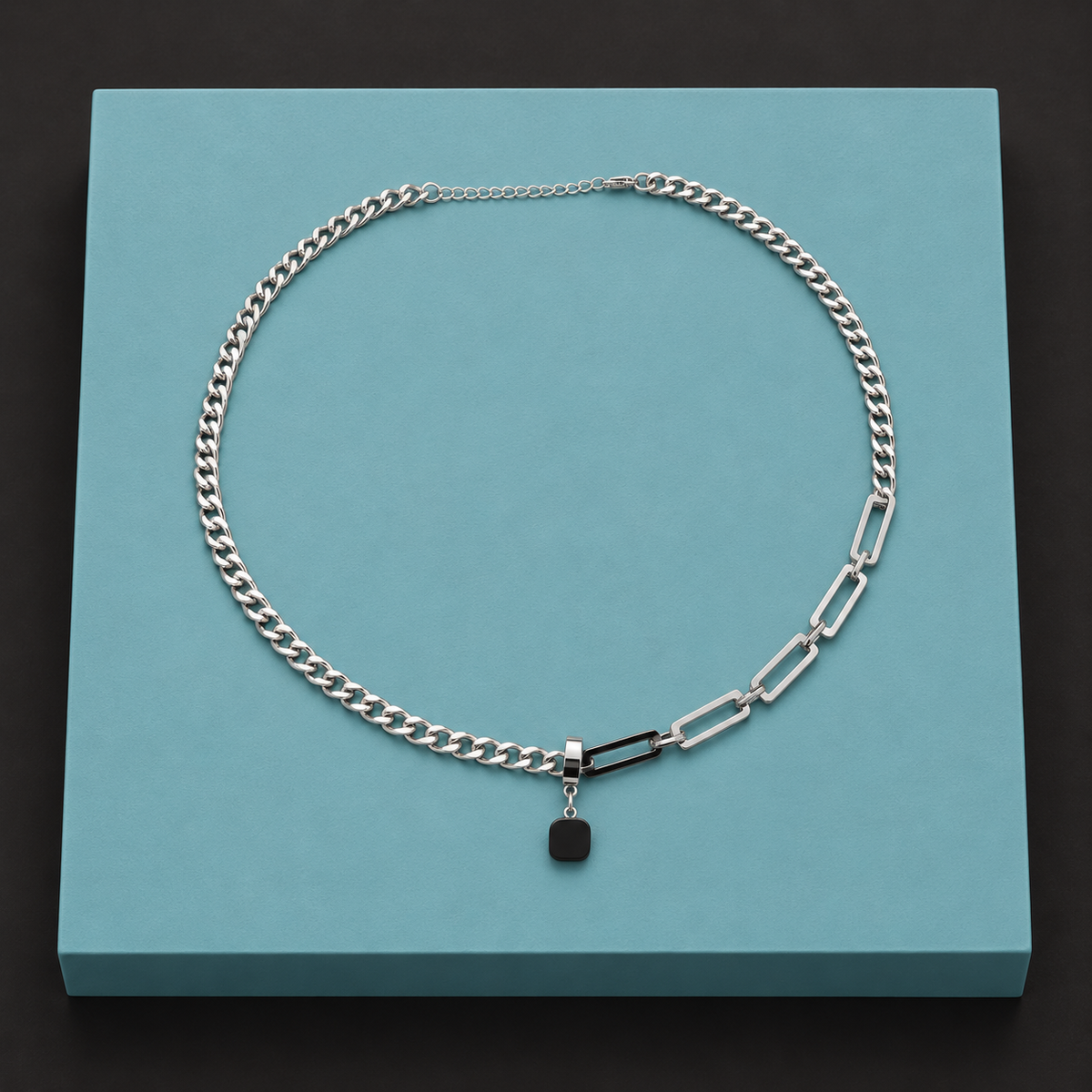 Black pendant necklace arranged on an aqua display block