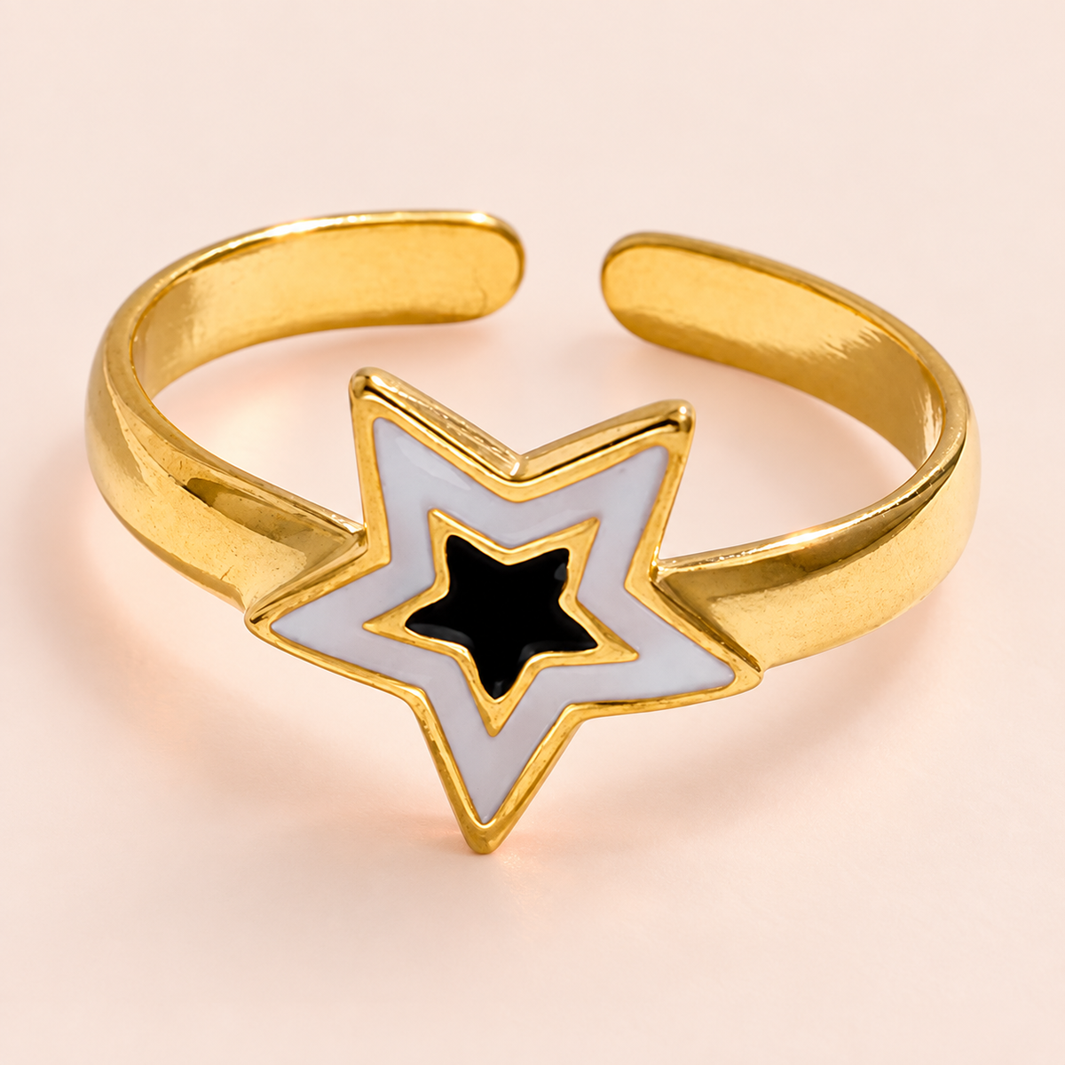 Gold-tone open-back ring with a pale and black nested-star motif