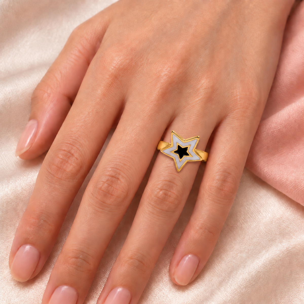 Nested-star ring shown on a hand resting on pale fabric