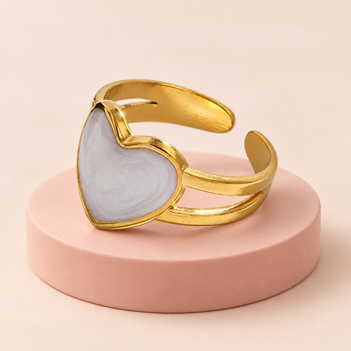 Pale heart open-back ring displayed on a blush pedestal