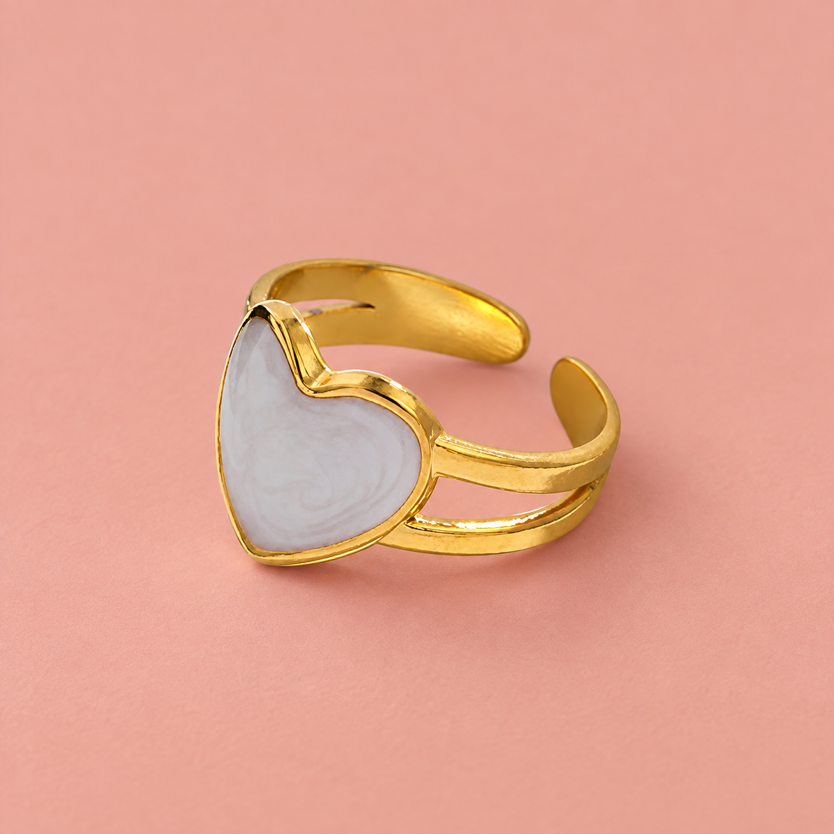 Pale heart and gold-tone ring on a blush background