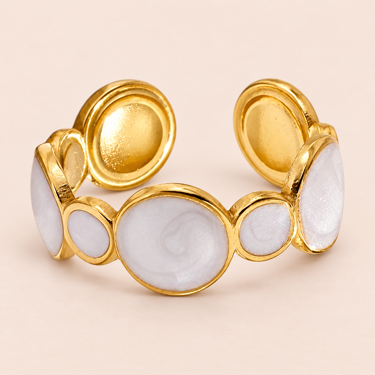 Gold-tone open-back ring with alternating pale circular motifs