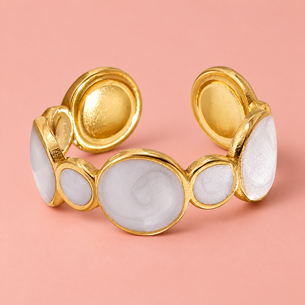 Pale circular-motif ring on a blush surface