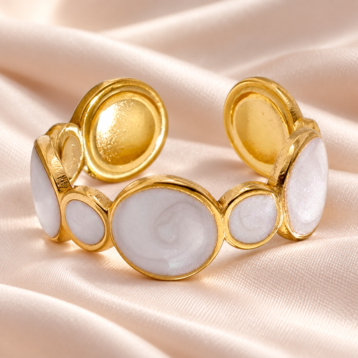 Circular-motif ring arranged on pale folded fabric