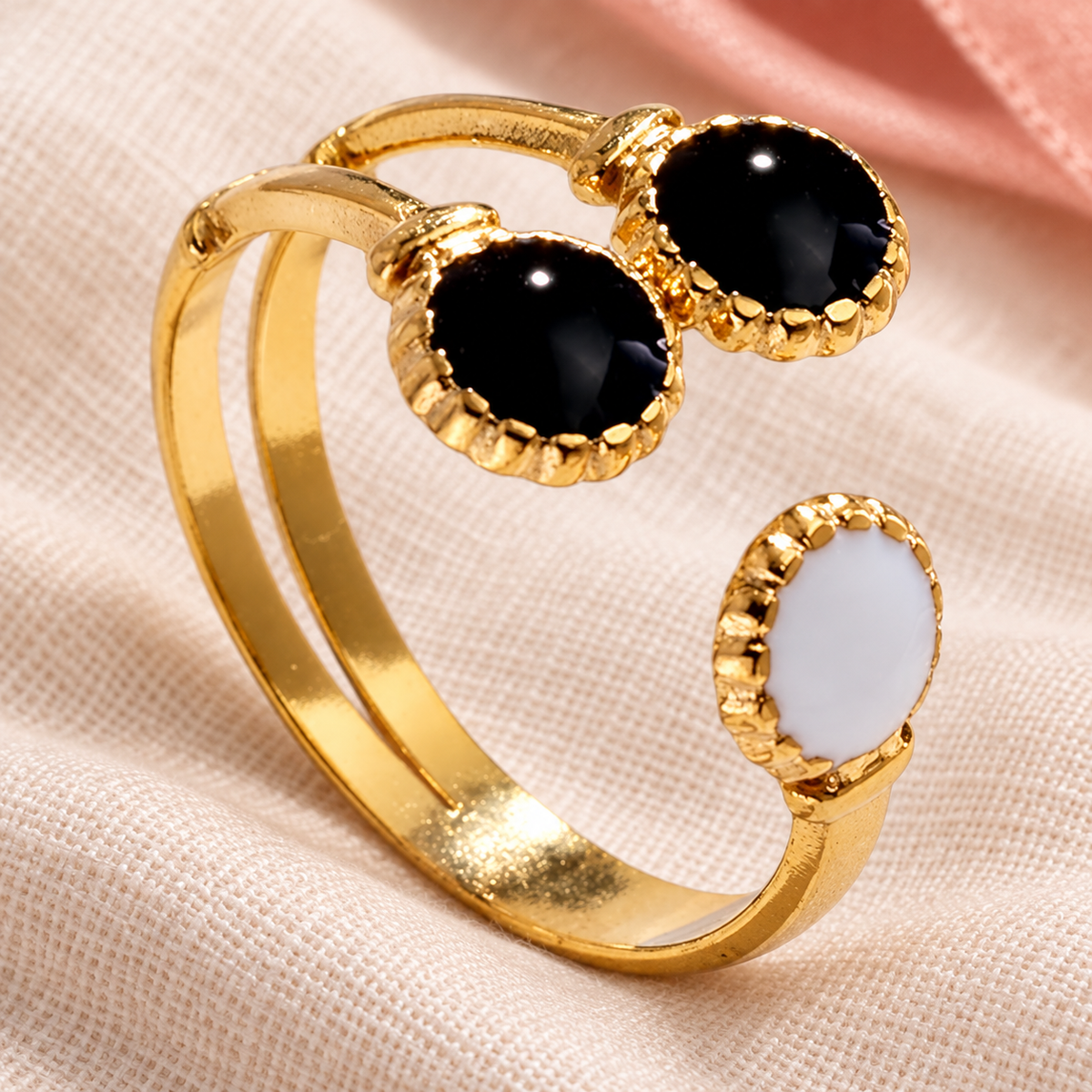 Three-motif ring resting on pale woven fabric