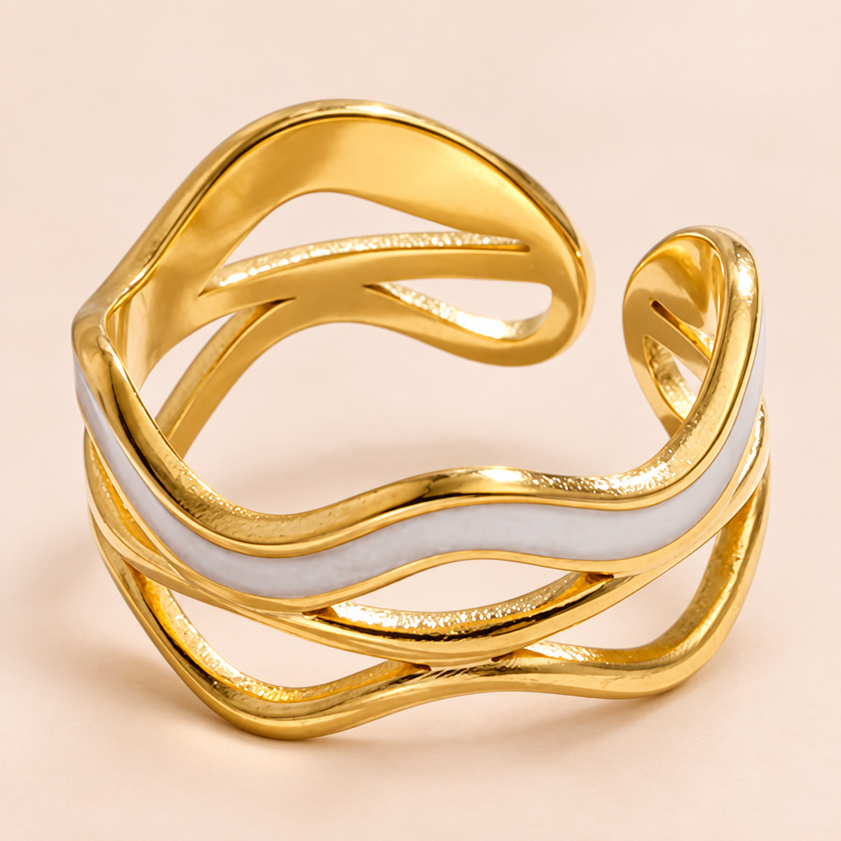 Gold-tone open-back ring with a pale wave and crossing bands