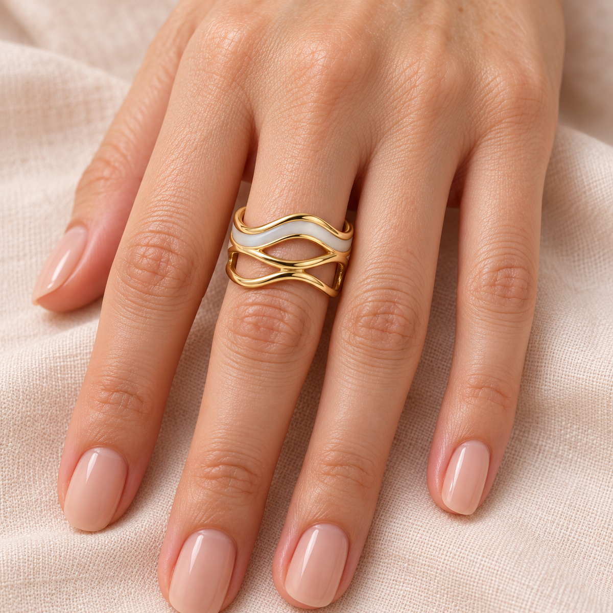 Pale wave and gold-tone openwork ring shown on a hand