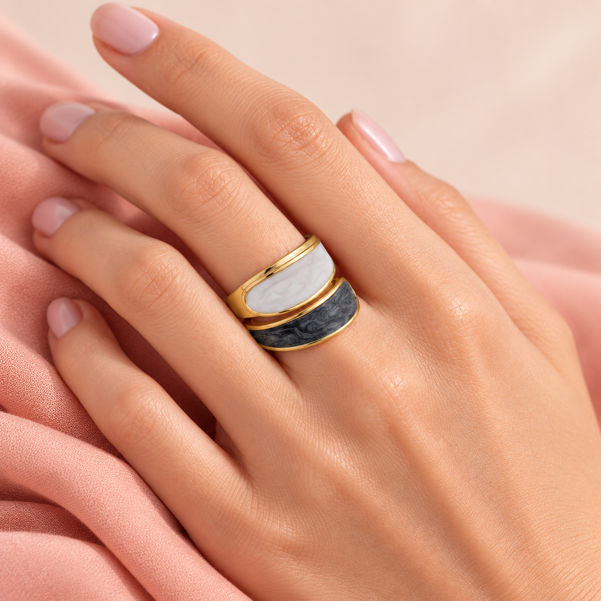 Pale and dark panel ring shown on a hand with blush fabric
