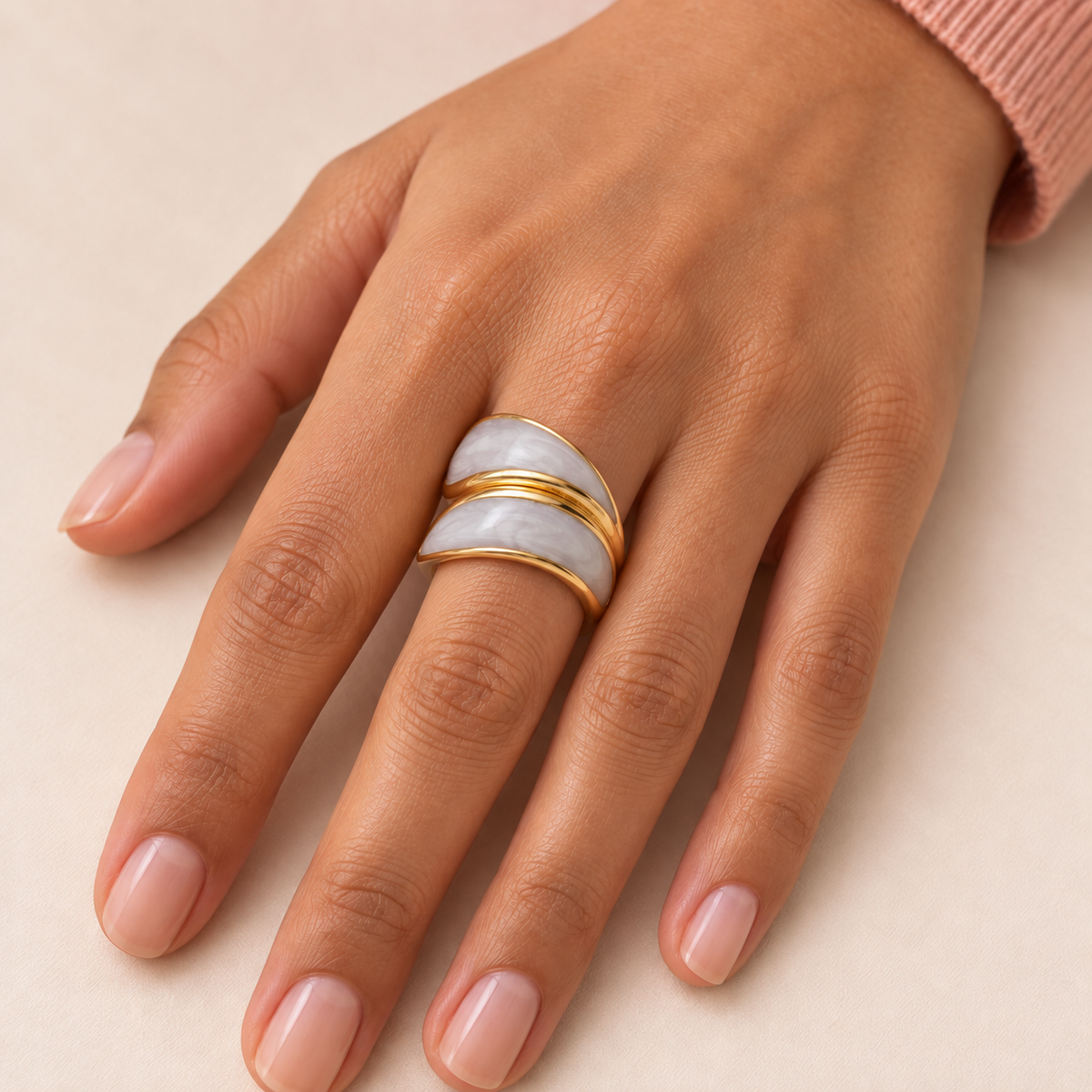 Curved pale-panel ring shown on a hand resting on a light surface