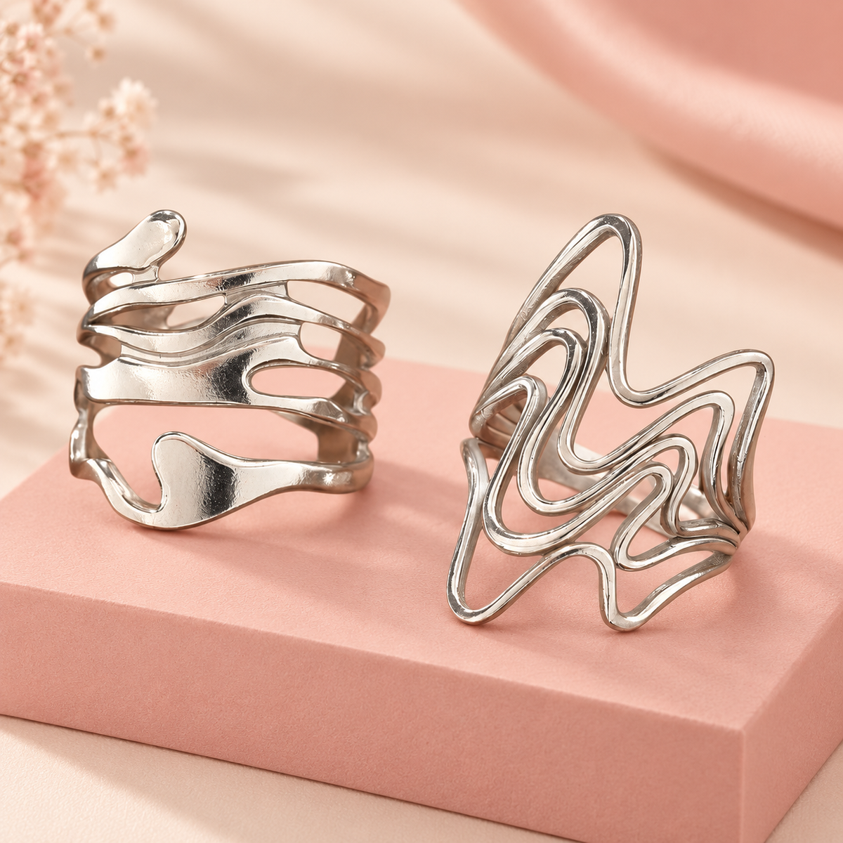 Silver-Tone Sculptural Ring Designs sculptural designs on a pink block