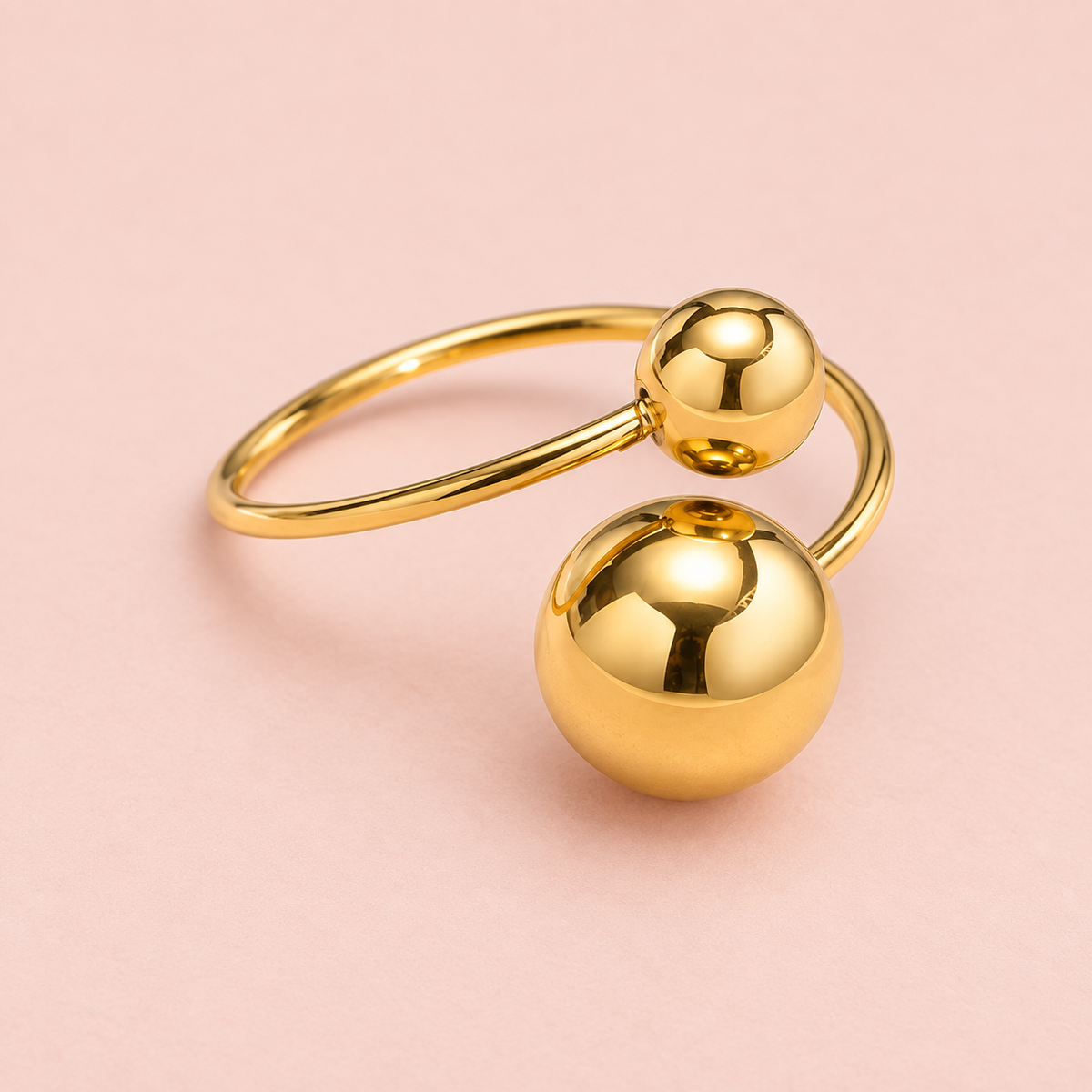 Gold-Tone Double-Sphere Open Ring for Women on a softly coloured surface