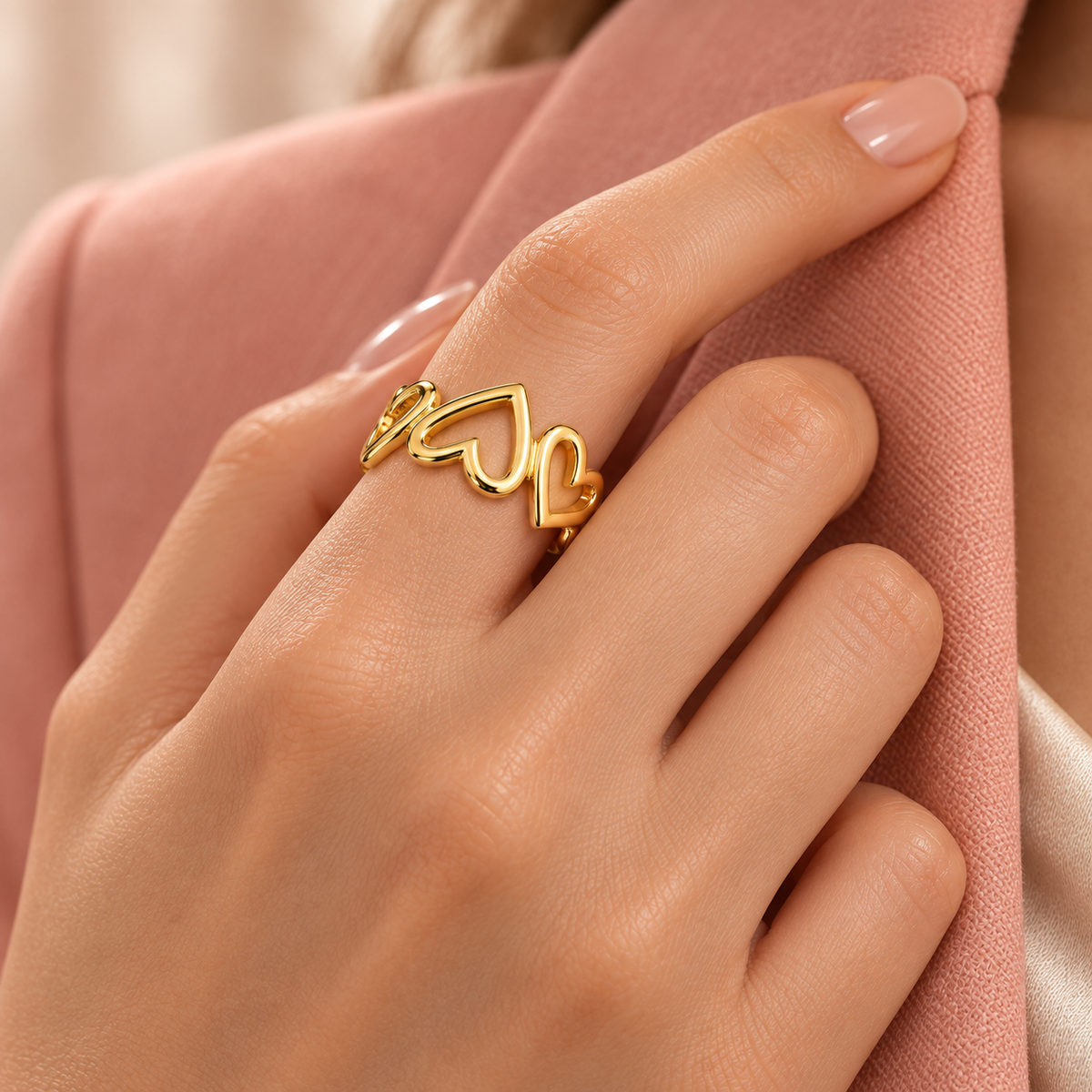 Gold-tone open ring with linked heart outlines styled on a hand