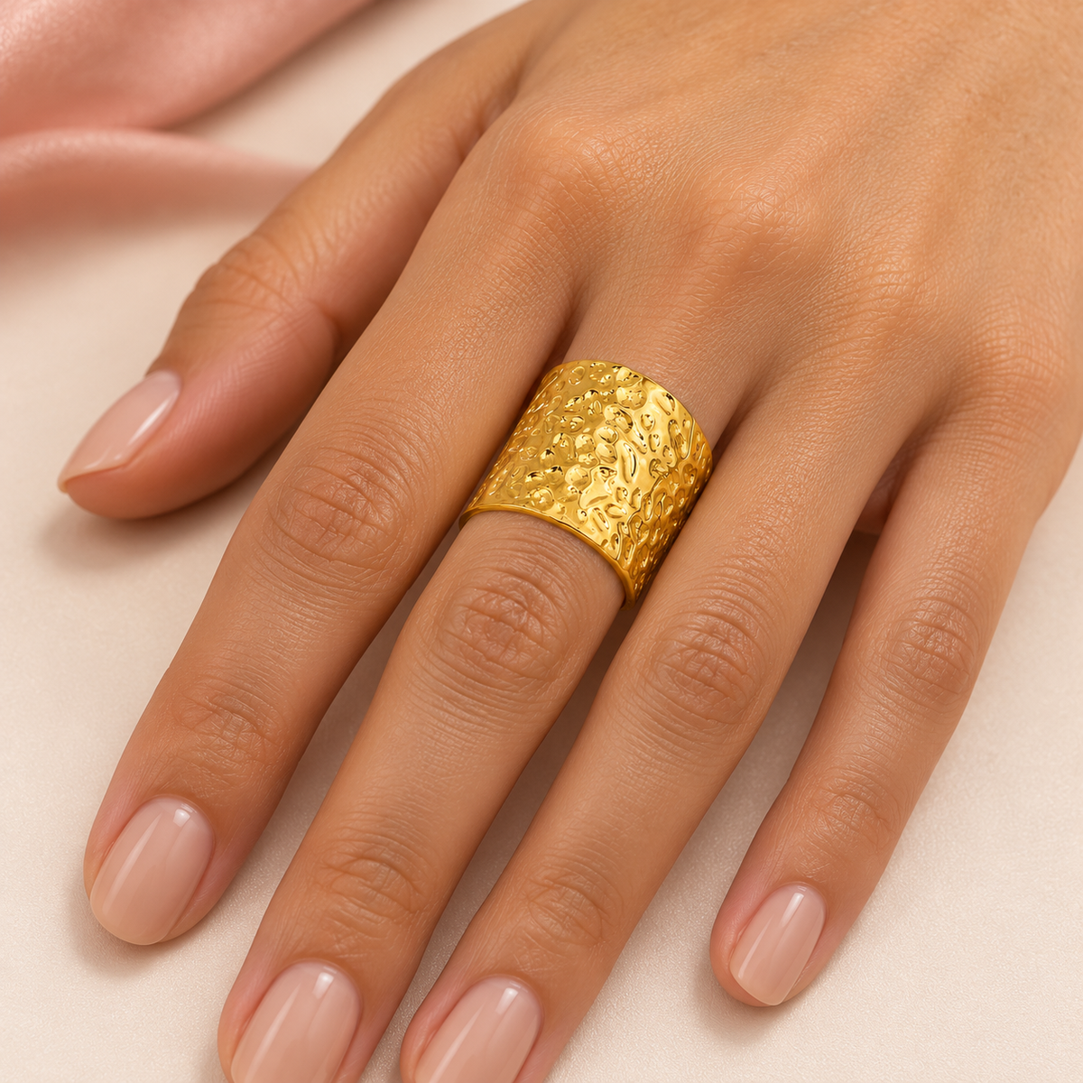 Gold-tone wide open band ring with a hammered texture styled on a hand