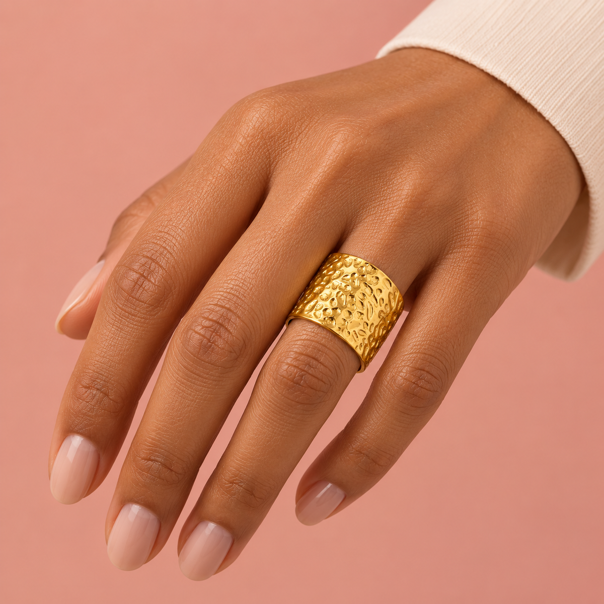 Gold-tone wide open band ring with a hammered texture styled on a hand