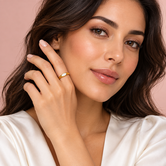Gold-tone ring with white oval detail, shown on a hand.