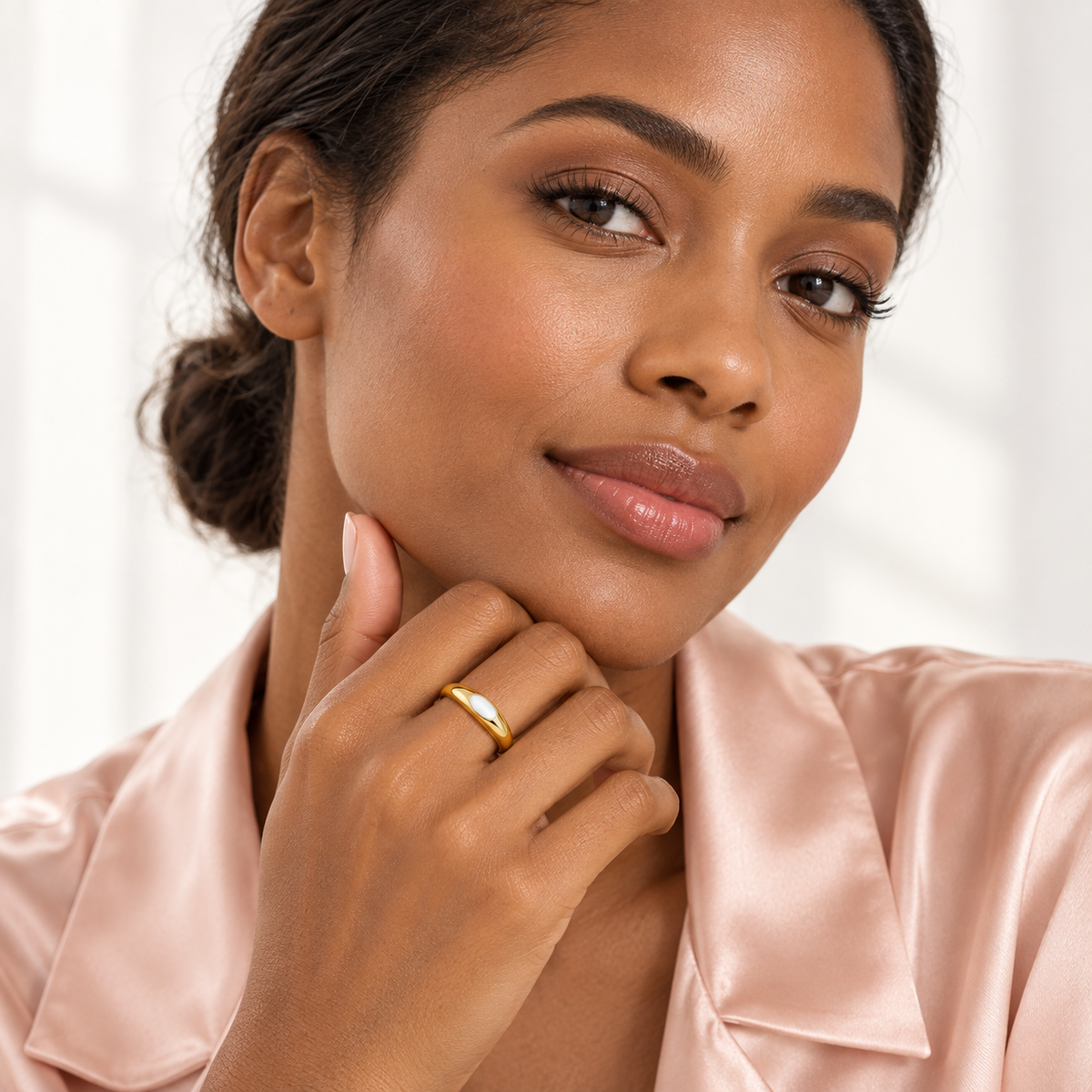 Gold-tone ring with white oval detail, shown on a hand from another angle.
