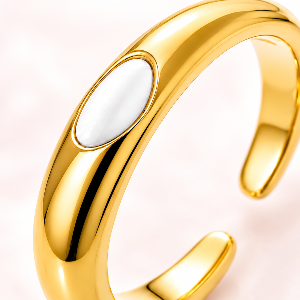 Gold-tone ring with white oval detail, close-up view.