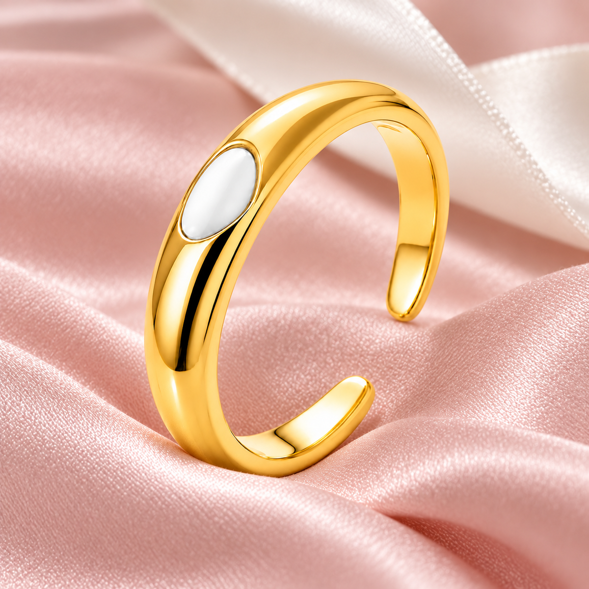 Gold-tone ring with white oval detail, still-life view on fabric.