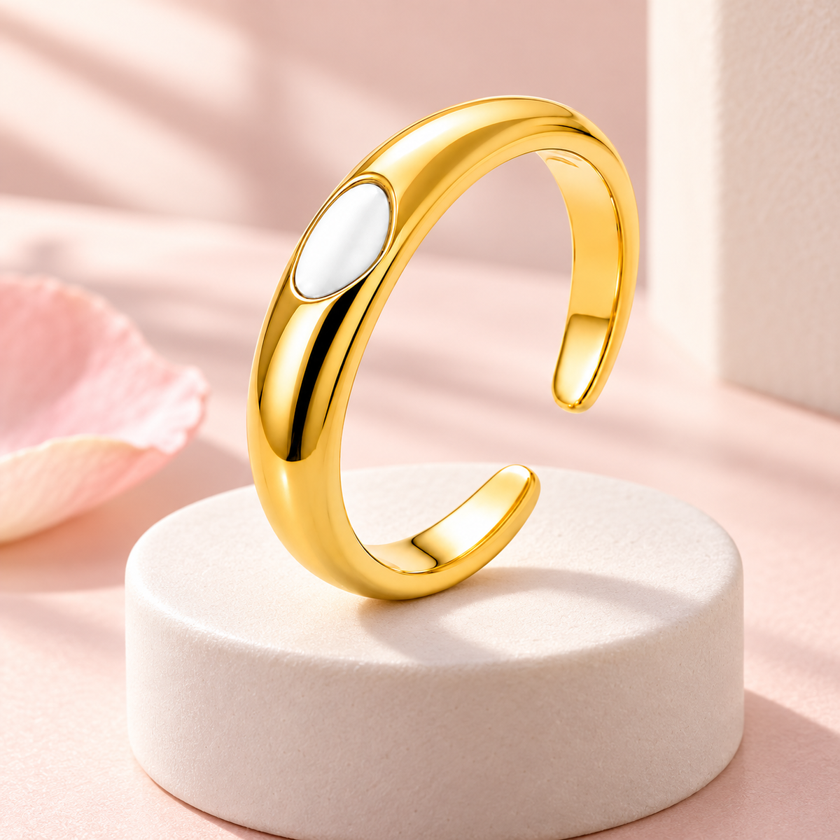 Gold-tone ring with white oval detail, styled product view.