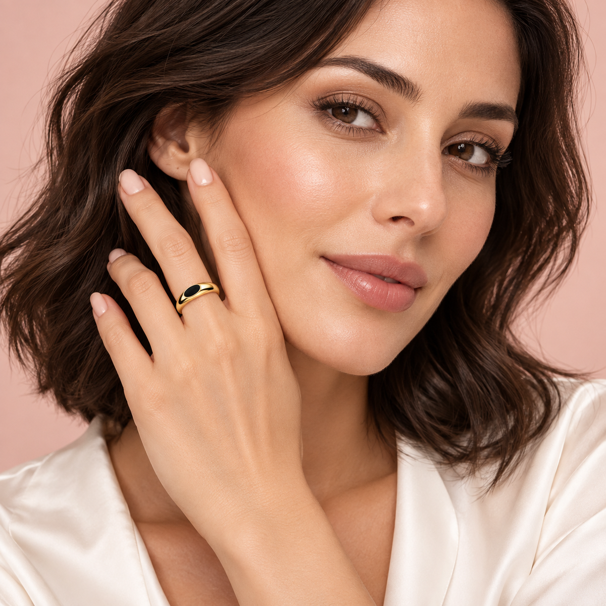 Gold-tone ring with black oval detail, shown on a hand.