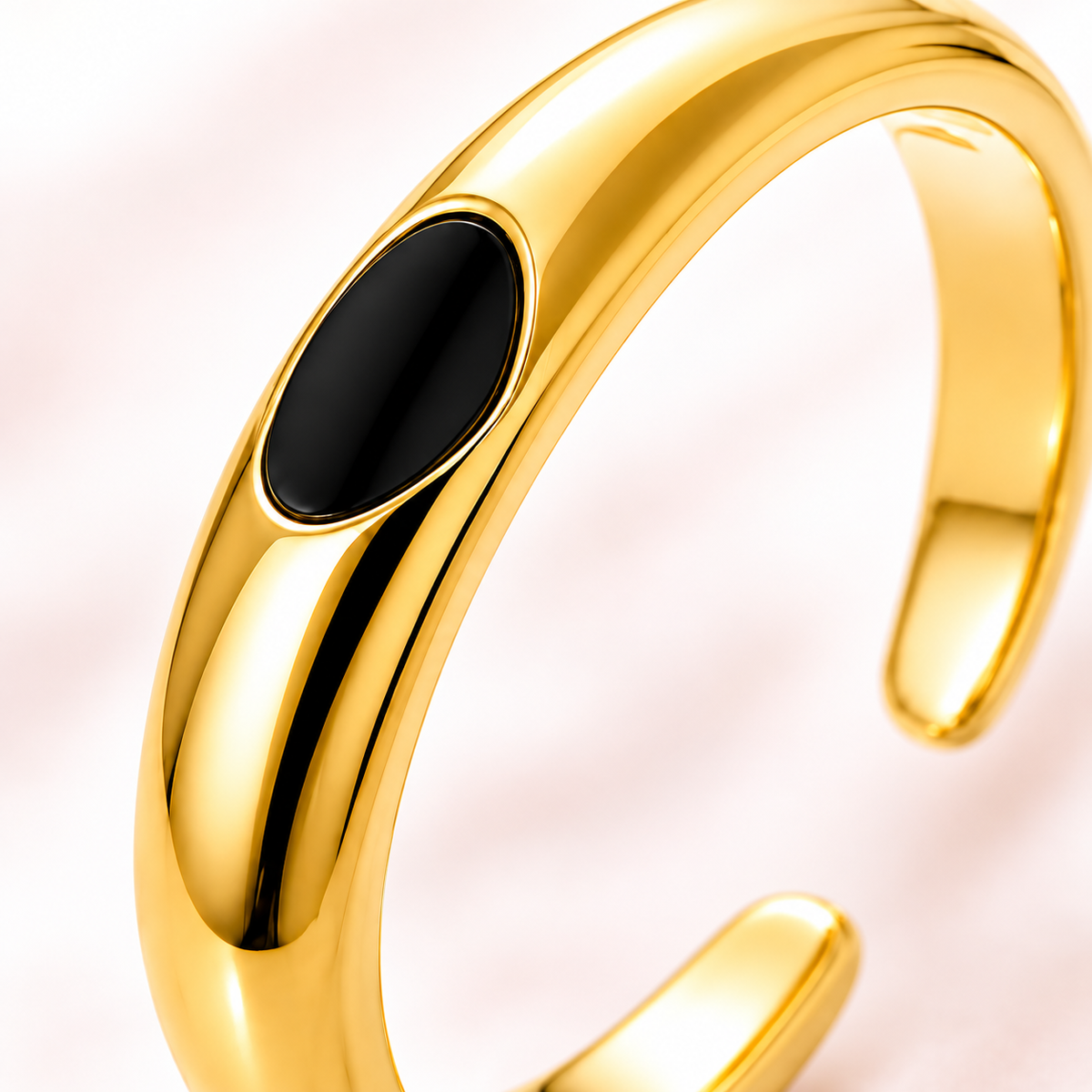Gold-tone ring with black oval detail, close-up view.