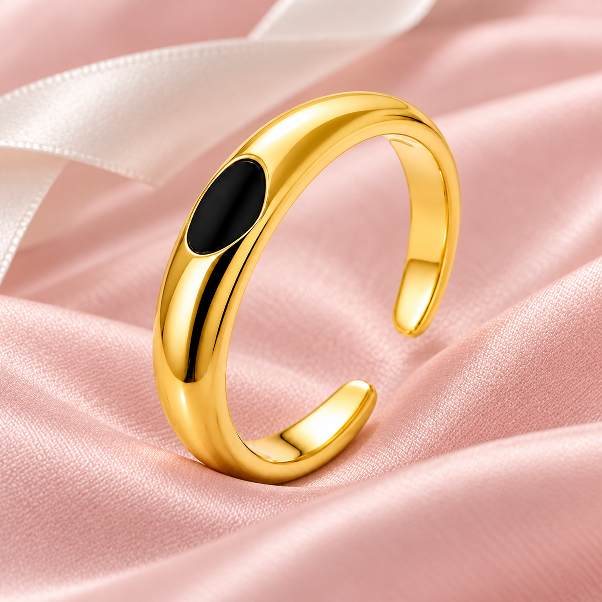 Gold-tone ring with black oval detail, still-life view on fabric.