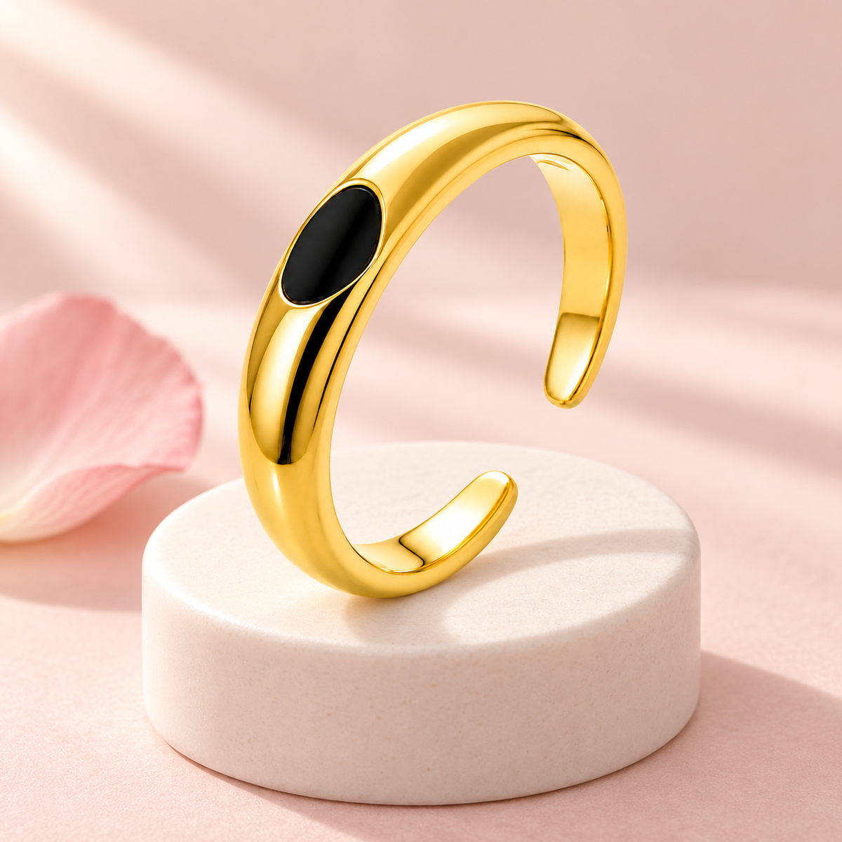 Gold-tone ring with black oval detail, styled product view.