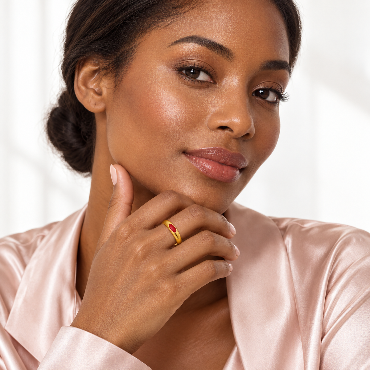 Gold-tone ring with red oval detail, shown on a hand from another angle.