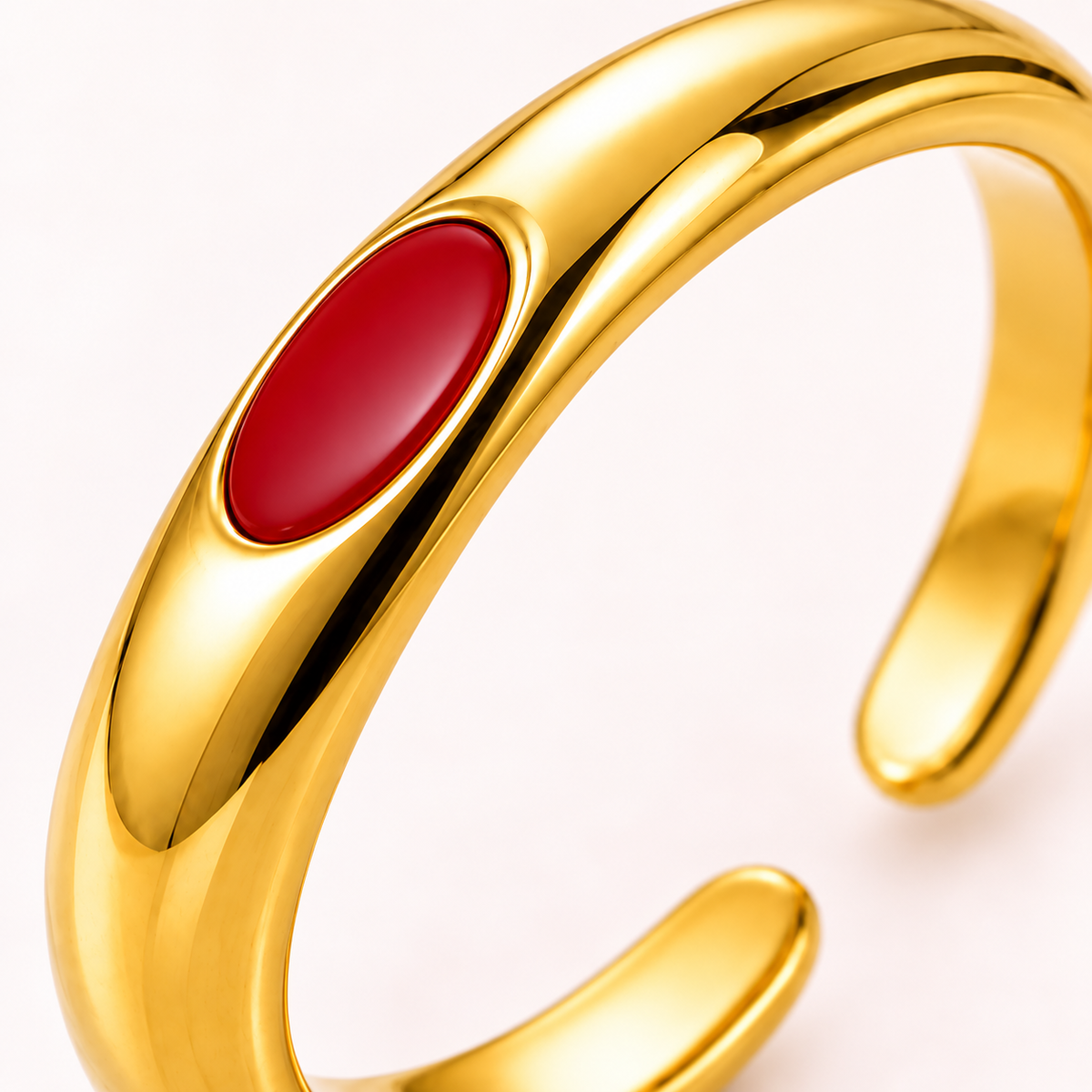 Gold-tone ring with red oval detail, close-up view.