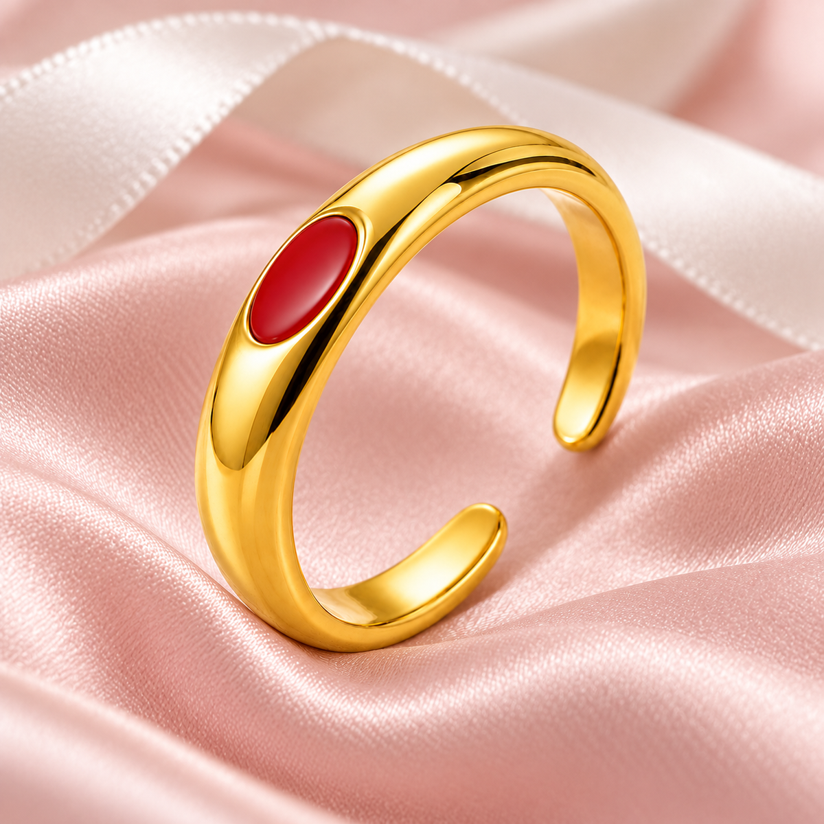 Gold-tone ring with red oval detail, still-life view on fabric.