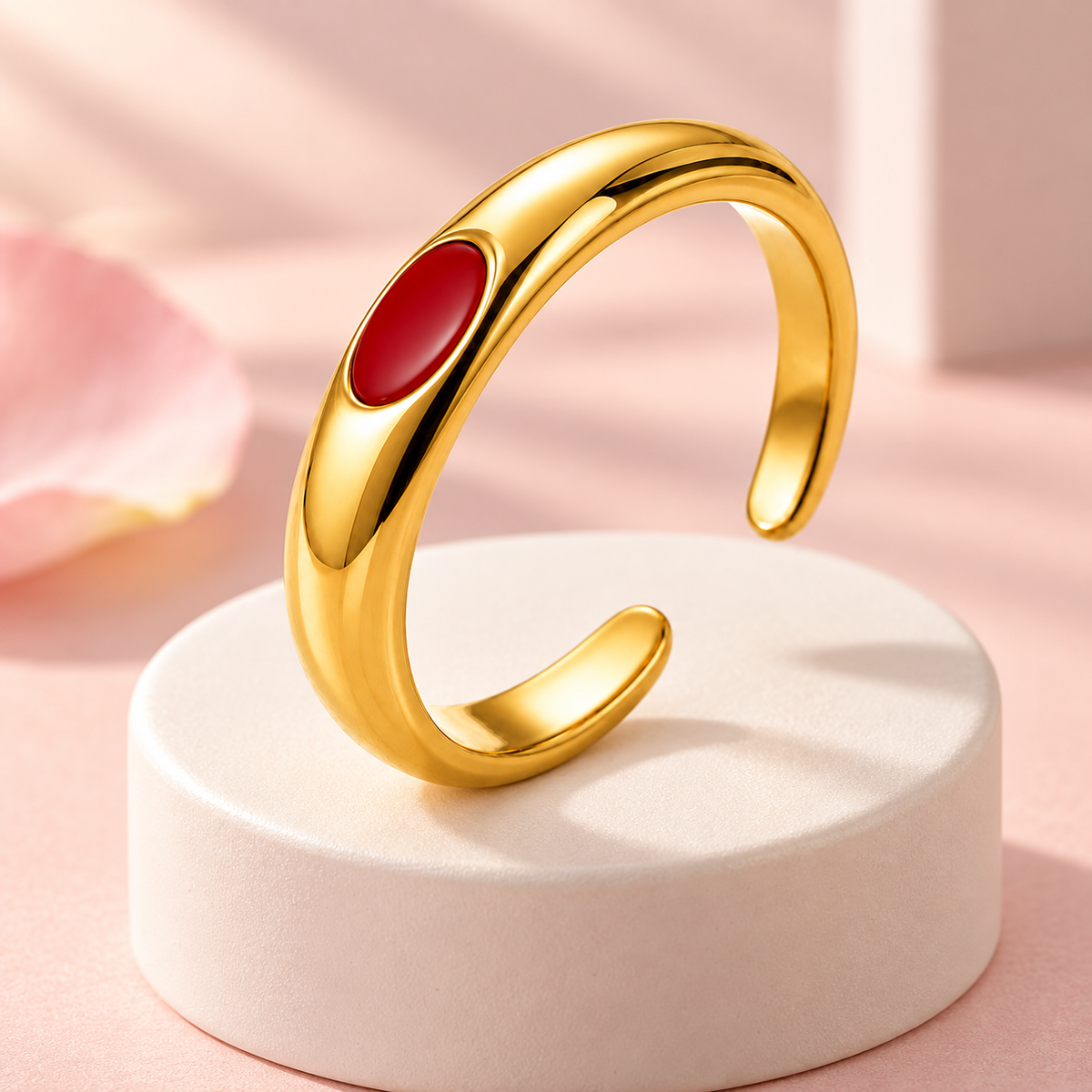Gold-tone ring with red oval detail, styled product view.