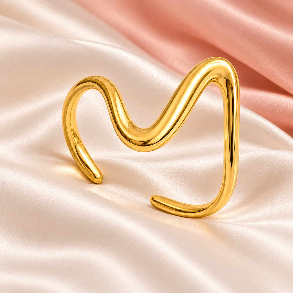 Gold-tone asymmetric wave ring, still-life view on fabric.