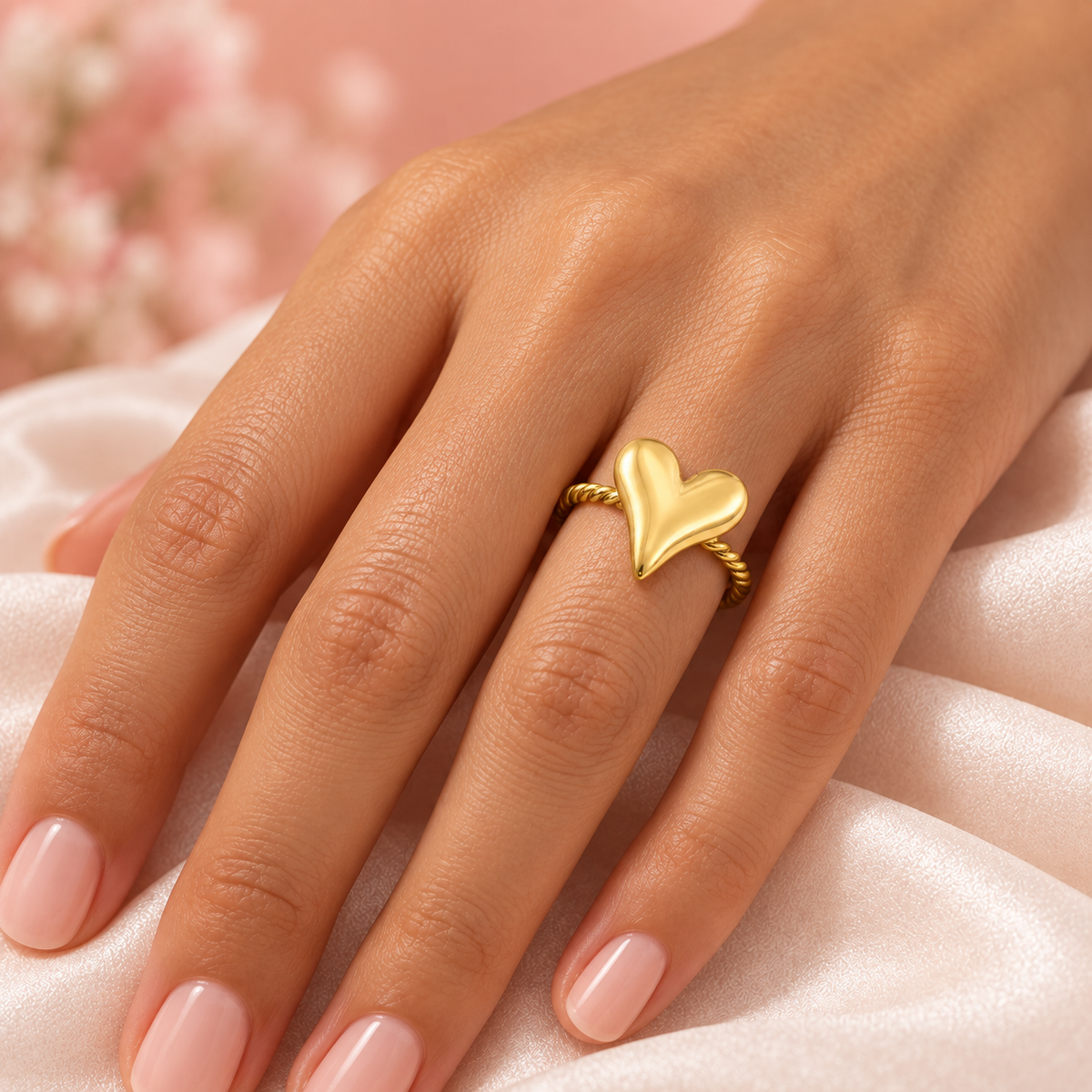 Gold-tone heart and rope ring, shown on a hand.