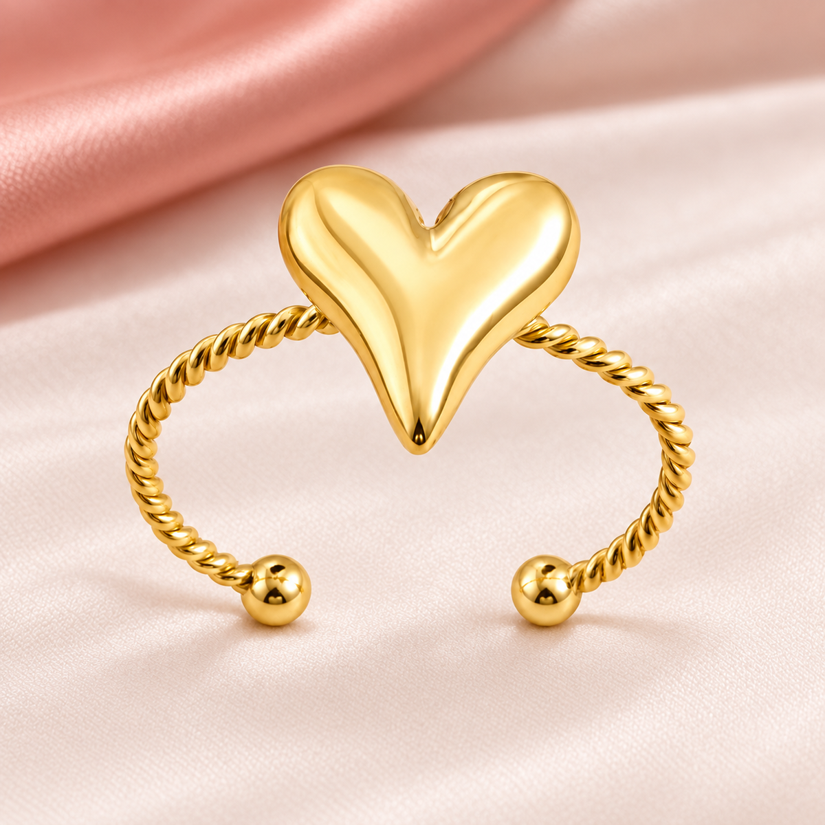 Gold-tone heart and rope ring, still-life view on fabric.