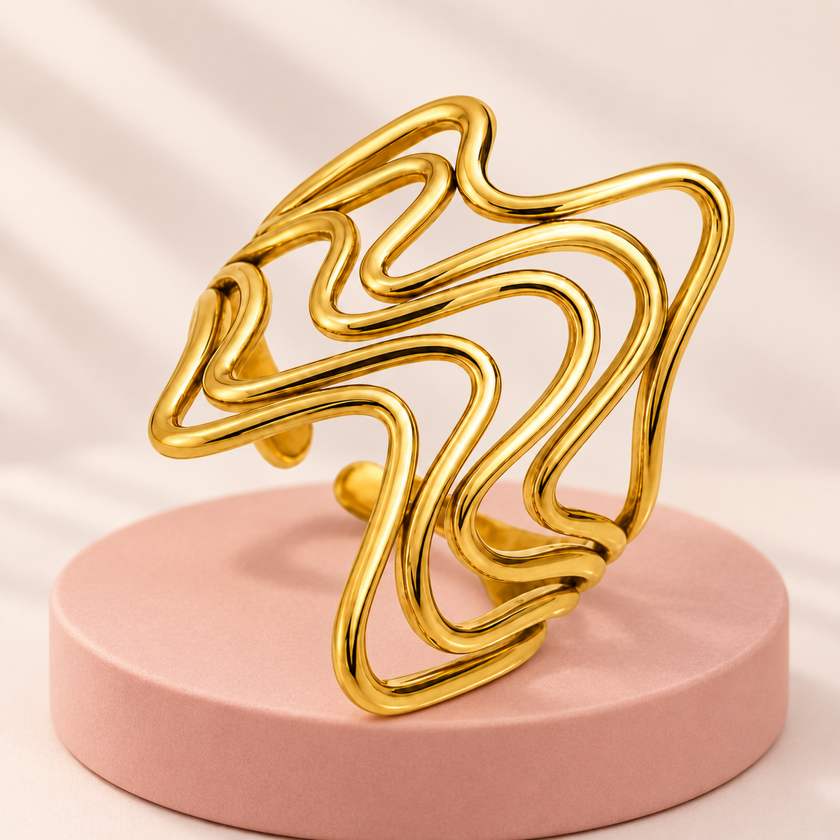 Gold-tone flowing wave ring, styled product view.
