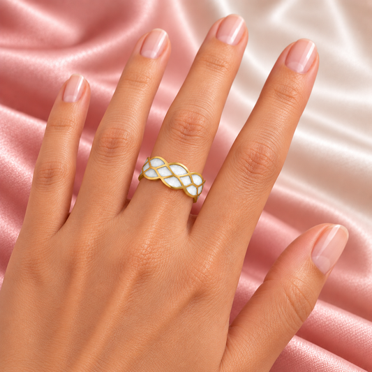 Gold-tone ring with white mosaic pattern, shown on a hand.
