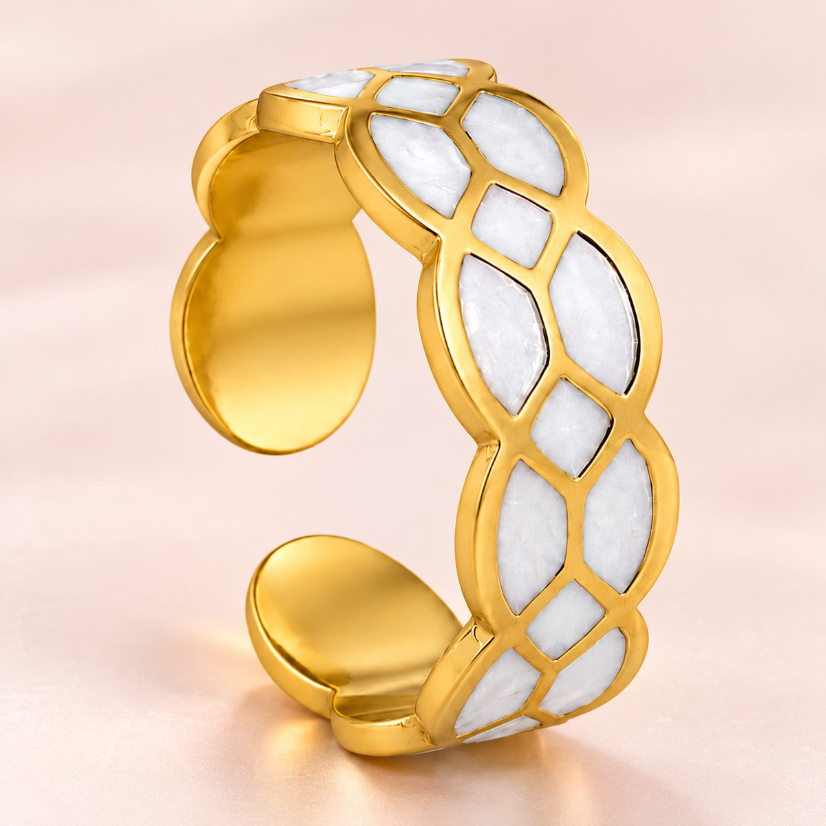 Gold-tone ring with white mosaic pattern, close-up view.
