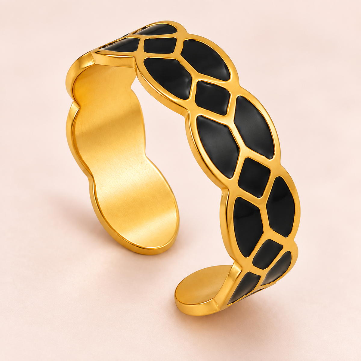 Gold-tone ring with black mosaic pattern, close-up view.
