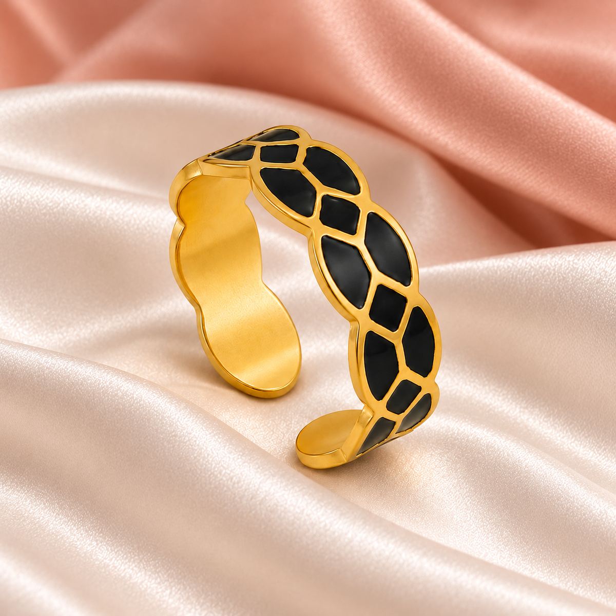 Gold-tone ring with black mosaic pattern, still-life view on fabric.