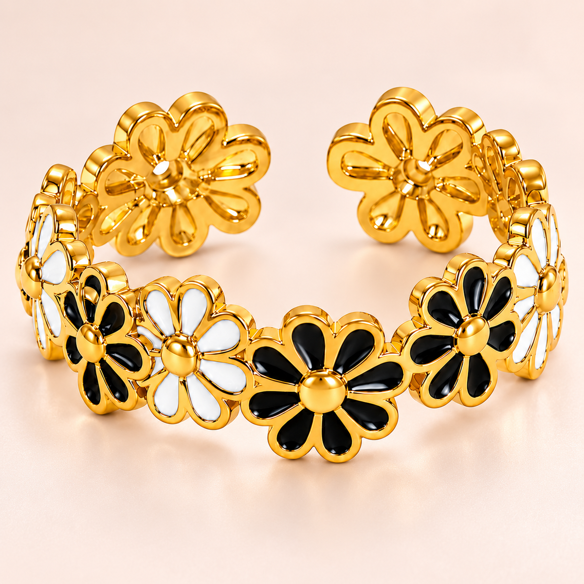 Gold-tone ring with black and white flowers, close-up view.