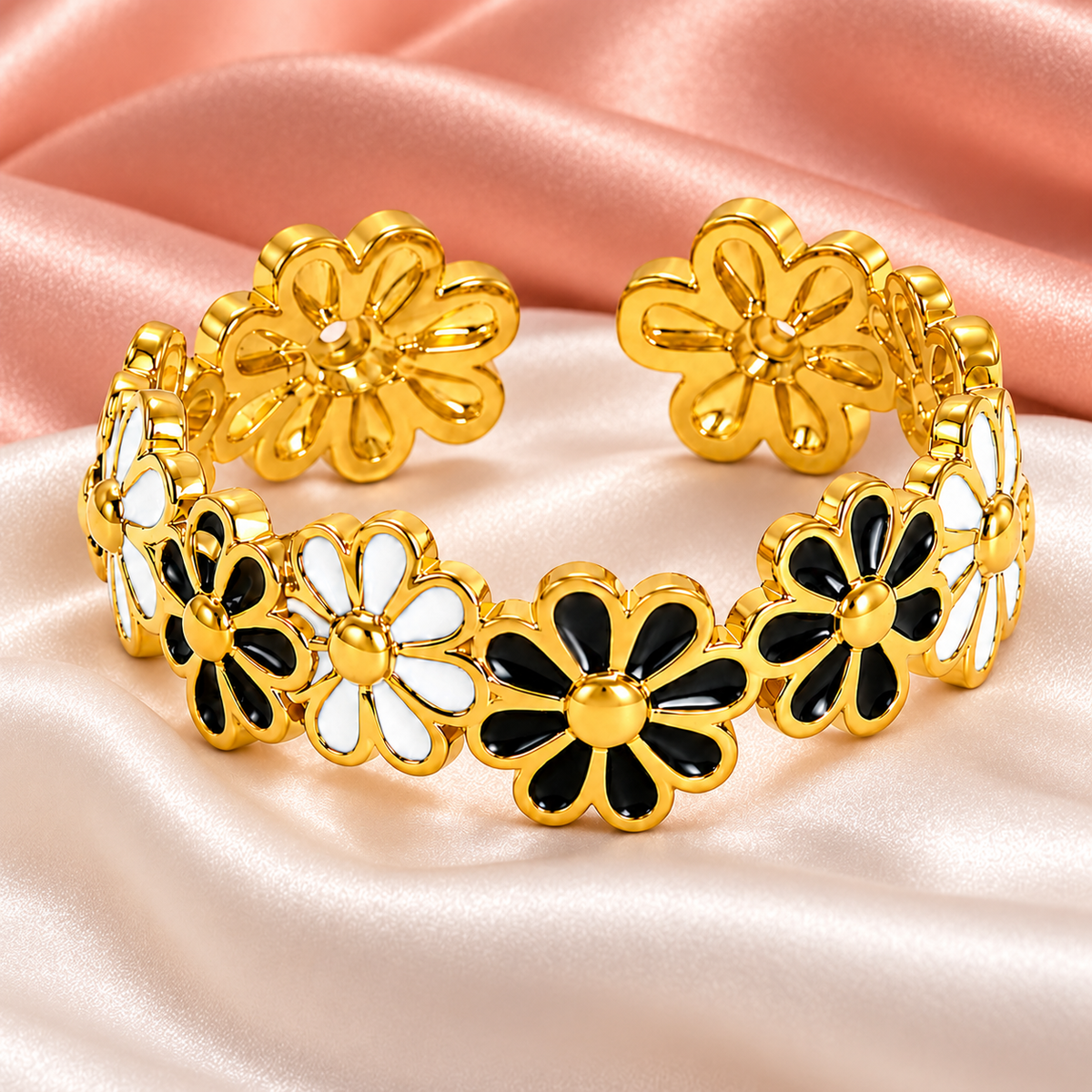 Gold-tone ring with black and white flowers, still-life view on fabric.
