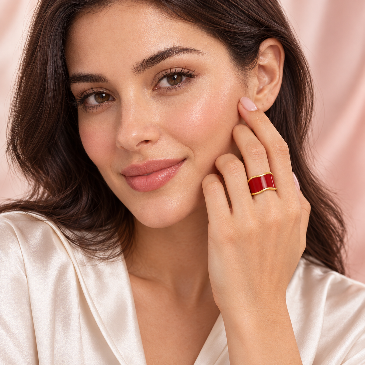 Red wave ring with gold-tone edges, shown on a hand.