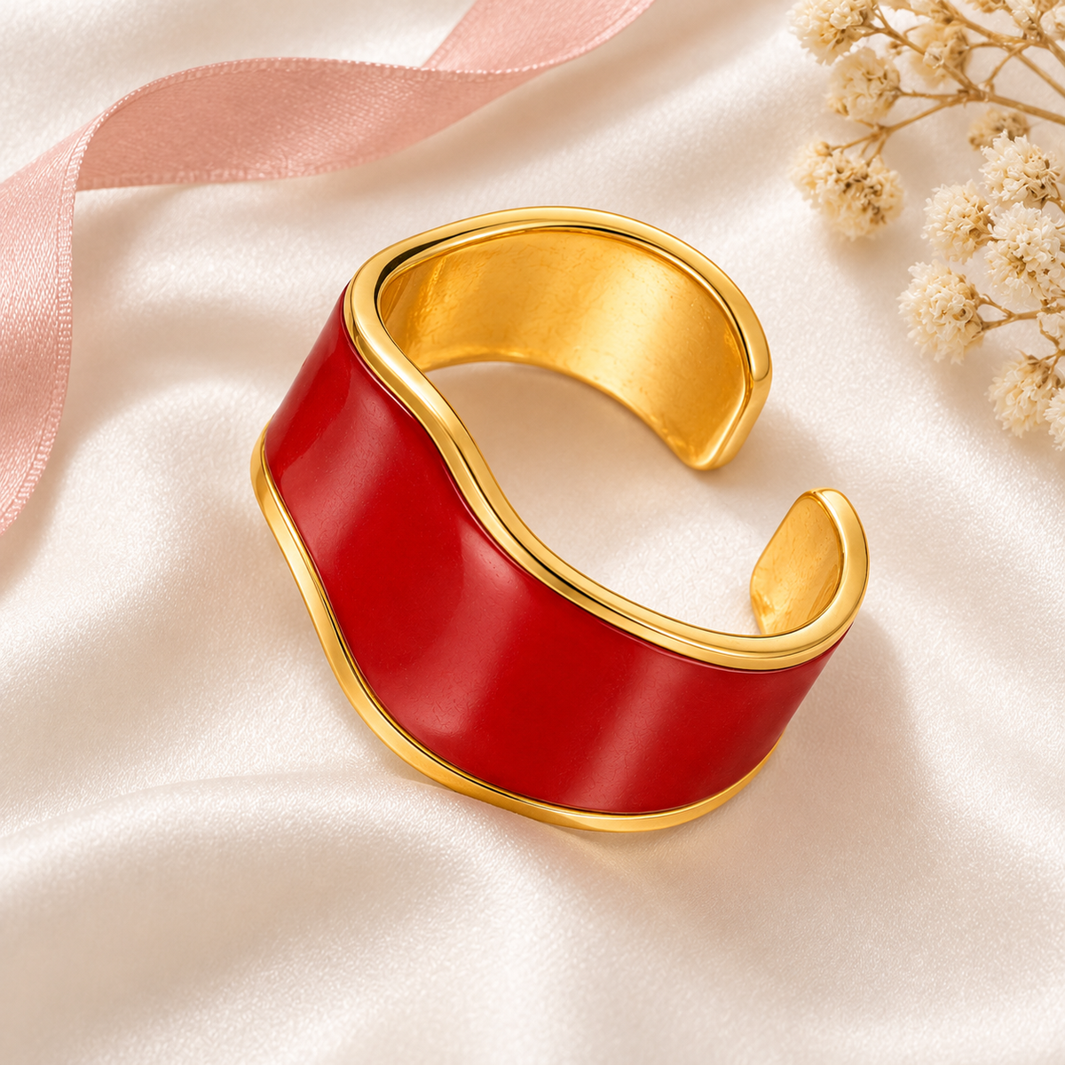 Red wave ring with gold-tone edges, still-life view on fabric.