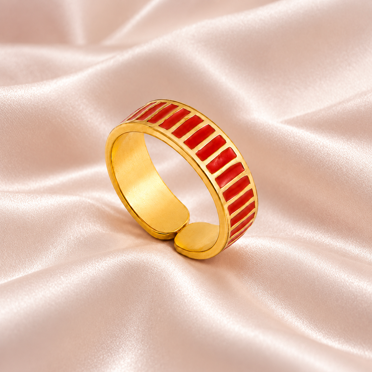 Gold-tone ring with red stripes, still-life view on fabric.